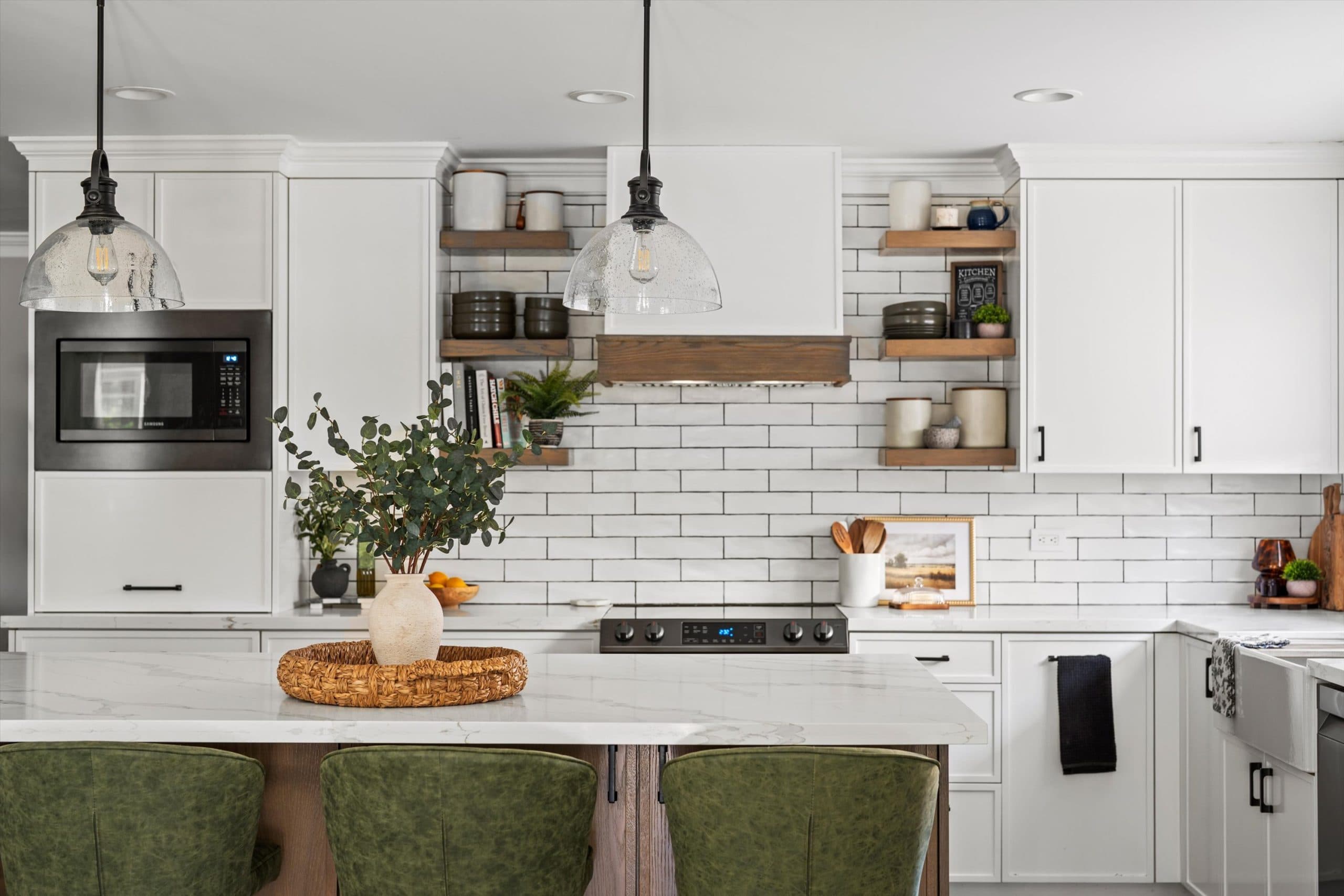 Full view of remodeled kitchen featuring white shaker cabinetry, natural wood accent island, open floating shelves, white subway tile backsplash, black pendant lighting, and hardwood floors