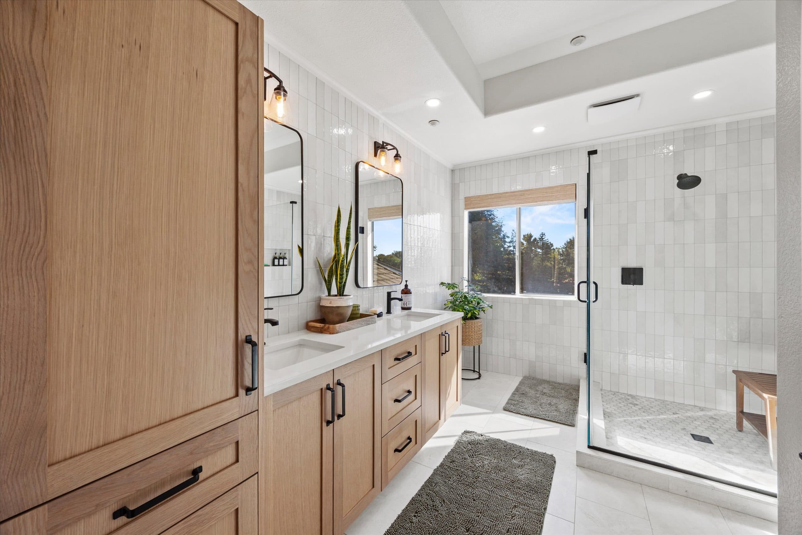 Custom oak vanity cabinetry with dual mirrors and walk-in shower in a remodeled bathroom