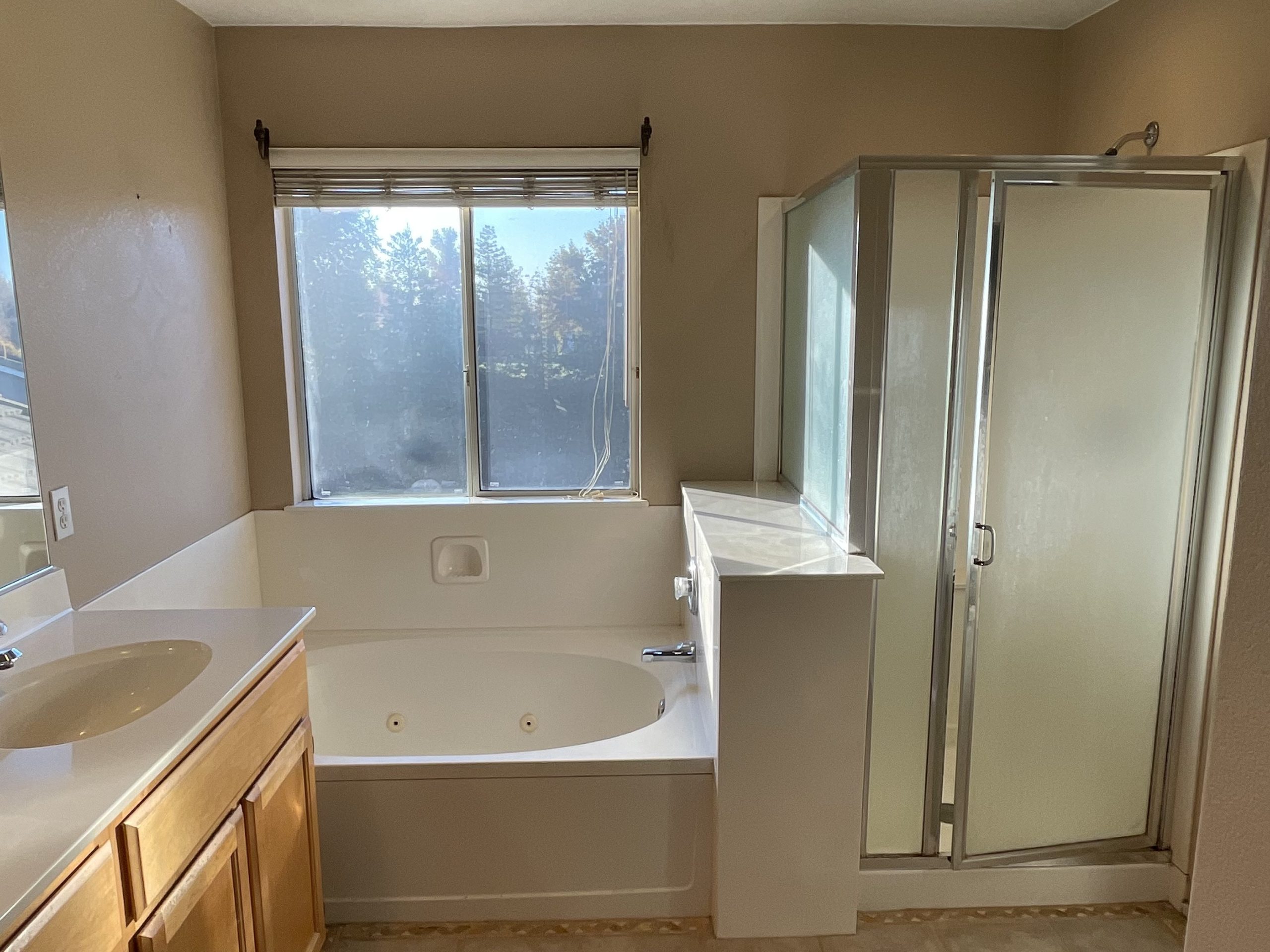 An image of a bathroom prior to renovation, featuring a shower and sink, illustrating its current state and potential for upgrades.