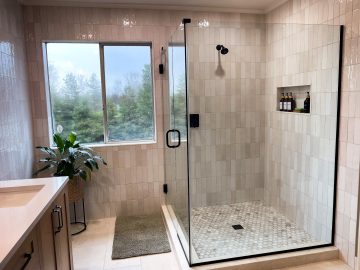 Renovated modern bathroom with a stylish glass shower door, highlighting contemporary design elements.